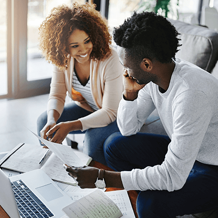 couple sitting on couch looking at bank statements