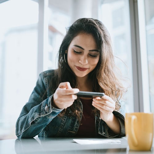 woman looking at phone sitting at table