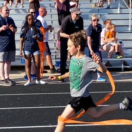 Child running in a track meet with cheering fans 