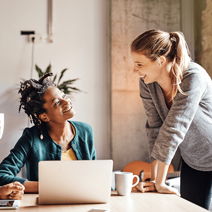 two women looking at laptop smiling