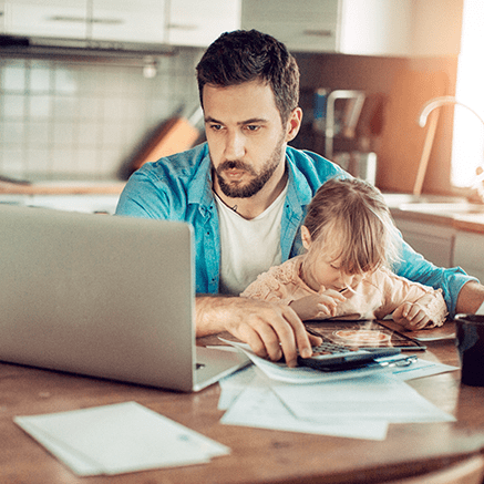 man working at table with daughter on lap