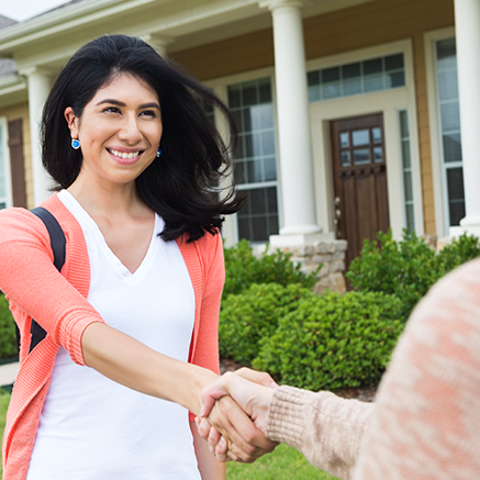 woman shaking hands with real estate agent outside of new home