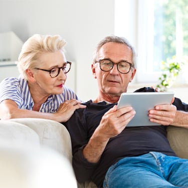 Older couple looking at tablet together on couch